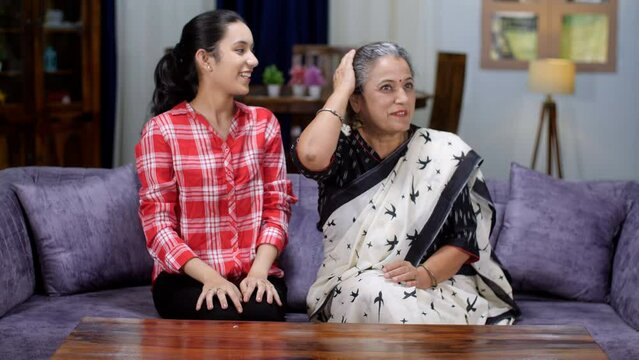 A young teenage girl putting a beautiful Gajra on her grandmother's hair - getting ready  auspicious occasion  South Indian. An old Indian lady with her beautiful granddaughter- generation gap  tak...