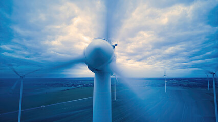 Close up of a wind turbine spinning over farmers fields during dusk, long exposure