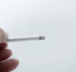 Cigarette in hand on a white background with copy space.