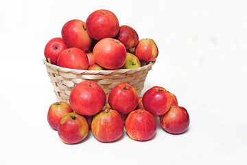Fototapeta na wymiar A lot of ripe, natural, red apples on a white background in a wicker basket, for advertising, for farmers, for healthy eating.