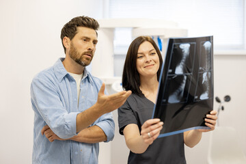 male patient looks on x-ray of the cervical spine with a doctor in a medical office