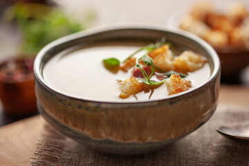 Pea soup with pieces of bacon, croutons and parsley in a bowl