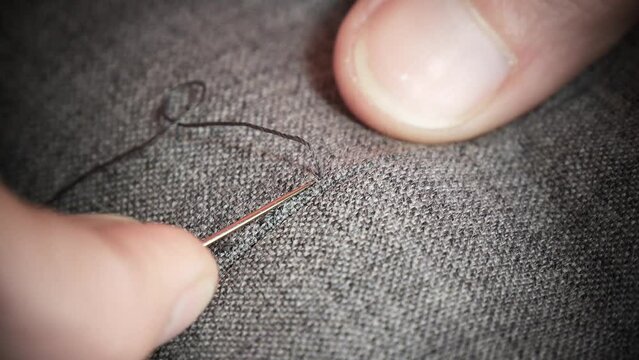 Hands of a seamstress who sews, with basting, a jacket of high Italian tailoring