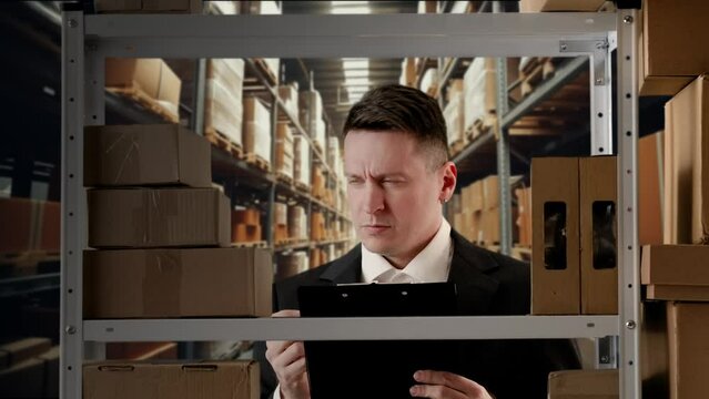 Portrait of storekeeper working in storage. Man manager in formal outfit near rack with boxes checks documents, frustrated confused.