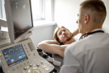 Ultrasound specialist examining lower abdomen of male patient. The concept of ultrasound diagnostics and men's health - obrazy, fototapety, plakaty