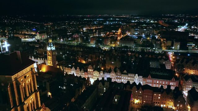 A mesmerizing drone film captures Gdańsk's city center at night in December. Glowing city lights and moving cars create a festive urban scene.