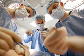 Scary surgeons look at the place of surgical intervention with horror during an operation, view...
