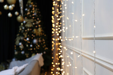 Interior of a festive New Year's room. Christmas atmosphere, sofa and Christmas tree, white walls. Happy New Year at home. Nice apartment, modern premises