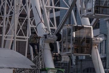 Kyiv, Ukraine - December 29, 2023: A man adjusts the Ferris wheel on Podil so that people can come and ride safely.