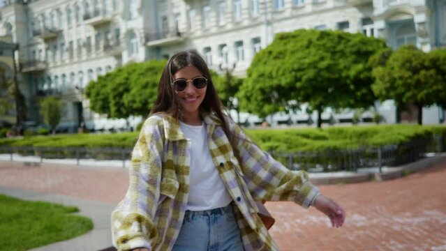 A young smiling girl walking around the city. Girl spinning happy in the park. A girl in the city, walking in the park. Girl spinning for the camera and smiling. Woman's portrait. High quality 4k