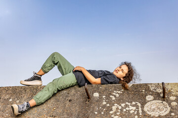 The girl is lying on a concrete wall(
