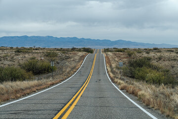 Lonely highway in extreme southwestern Arizona, with hills, leading into the mountans from the desert. Empty road