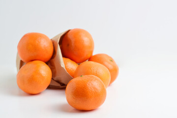 Group of tangerines in kraft paper bag.