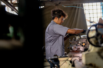 Asian worker in production plant drilling at machine. Professional worker near drilling machine on...