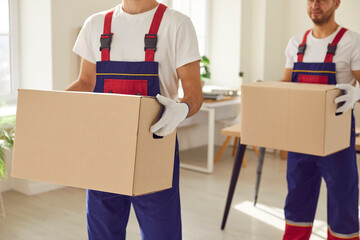 Cropped midsection shot of two male workers from a professional moving service carrying packed up...