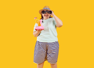 Portrait of happy smiling fat woman in hat and sunglasses holding orange juice cocktail in...