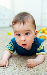 A Baby Laying on the Floor With a Surprised Look on His Face