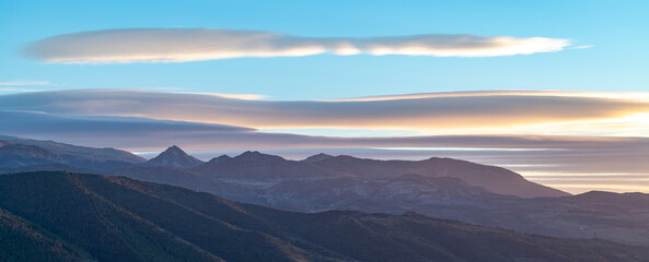 Sunset with spectacular lenticular clouds in the sky over the snowy peaks of Sierra Nevada...