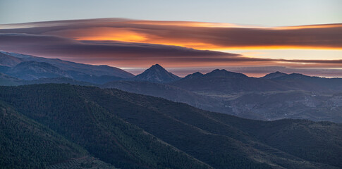 Sunset with spectacular lenticular clouds in the sky over the snowy peaks of Sierra Nevada...