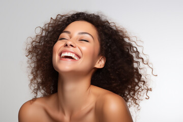 Beautiful happy Latin American woman takes care of her skin, posing over grey background