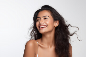 Beautiful laughing young Indian woman takes care of her skin, posing over grey background