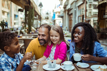 Happy Family Laughing Together at a Street Cafe