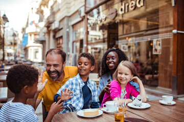 Happy Family Laughing Together at a Street Cafe