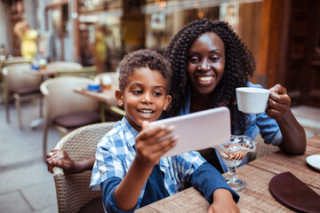 Mother and Son Enjoying a Video Call at an Outdoor Cafe