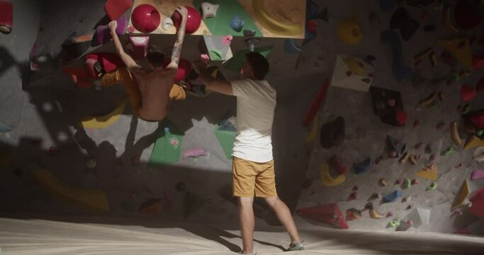 Anonymous men practicing climbing wall in gym