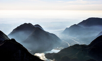 Beautiful panorama and view from the top of the Amariana mountain in Friuli Venezia Giulia. View of Lake Cavazzo and other nearby mountains. Foggy day which makes the atmosphere mystical.