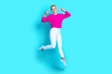 Fototapeta na wymiar Full length portrait of excited carefree person jump demonstrate v-sign near eyes isolated on turquoise color background