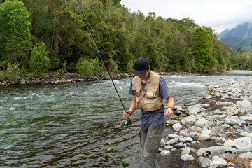 Young man walking along the riverbank while fishing.