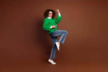 Fototapeta na wymiar Full length photo of overjoyed funky person use smart phone raise fist achieve like empty space isolated on brown color background
