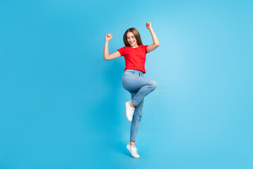 Fototapeta na wymiar Full length photo of crazy cheerful girl dressed trendy clothes jumping with raised hands isolated on blue color background