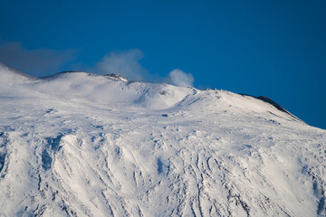 Fototapeta na wymiar Bronte town under the snowy and majestic volcano Etna and a cloudy blue sky