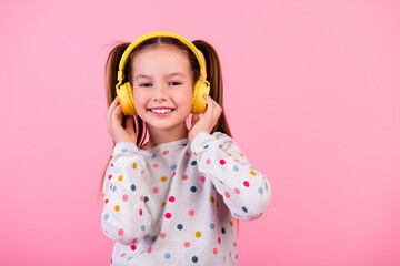 Portrait of good mood schoolgirl with ponytails dressed dotted sleepwear enjoy music in headphones...