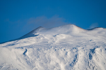 Fototapeta na wymiar Bronte town under the snowy and majestic volcano Etna and a cloudy blue sky