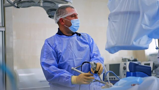 Attentive male Caucasian surgeon looking at the screen using surgical device. Endoscopic surgery in hospital.