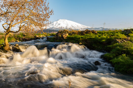 A seasonal river flows under the massive snowcovered Etna volcano. Favare Santa Venera 