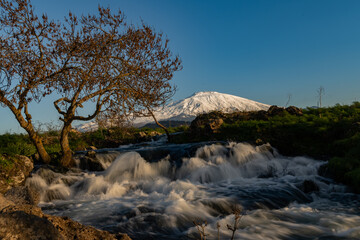 A seasonal river flows under the massive snowcovered Etna volcano. Favare Santa Venera 