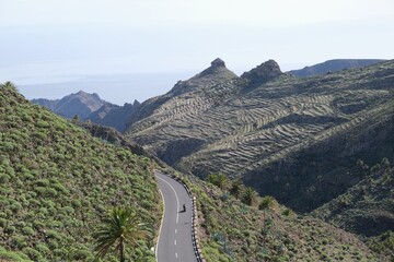 Fototapeta premium Motorcycle on winding asphalt road in mountains, trail from San Sebastian de la Gomera to El Cedro Forest in Garajonay National Park. La Gomera, Canary Islands, 