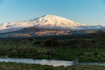 Bronte town under the snowy and majestic volcano Etna and a cloudy blue sky
