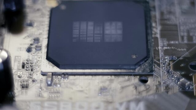 On the computer motherboard we see many capacitors and a processor. Closeup. Macro. Shallow depth of field. Shot in motion