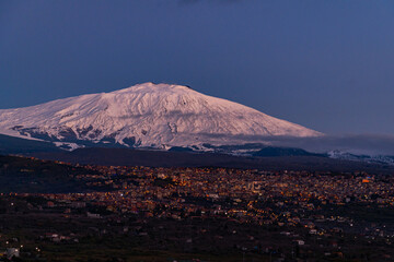 Bronte town under the snowy and majestic volcano Etna and a cloudy blue sky