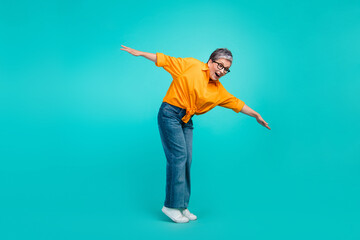 Full size photo of keep balance old woman falling into abyss dangerous tightrope wear orange shirt jeans isolated on blue color background