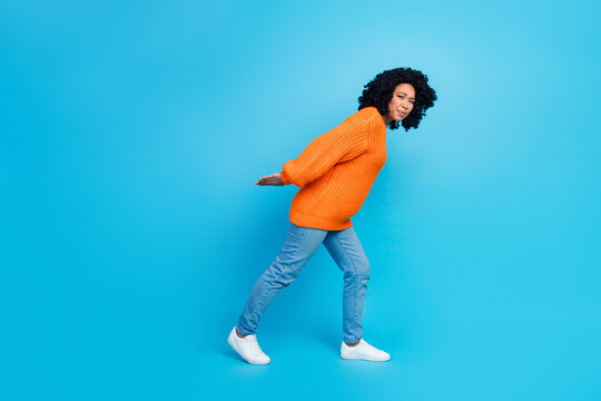 Full size photo of attractive young woman struggle carry empty space wear trendy knitwear orange clothes isolated on blue color background