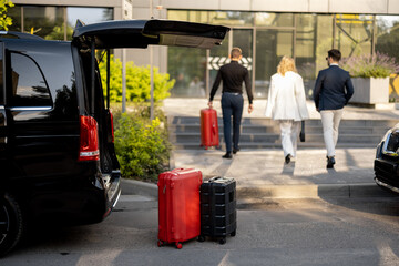 Driver or concierge helps a business couple carry their suitcases to the office or hotel from a...