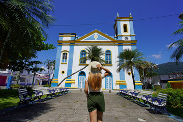 Tourism in Brazil. Back view of young tourist woman in front of the church Igreja Matriz in the...