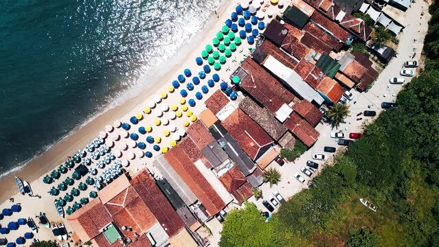 Beach with umbrellas and buildings on Brazilian coast, area of Paraty town