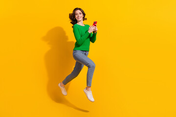 Fototapeta na wymiar Full body length photo of cheerful young energetic lady green pullover jeans addicted using cellphone isolated on yellow color background